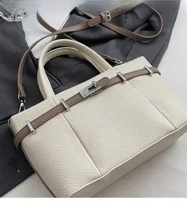Détail d'un sac en cuir beige à motif litchi avec fermoir rotatif en métal argenté