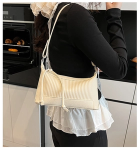 Détail du sac bandoulière plissé crème avec bandoulière nouée porté par un mannequin