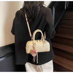 Detail of off-white Boston bag with plush bear charm and adjustable shoulder strap