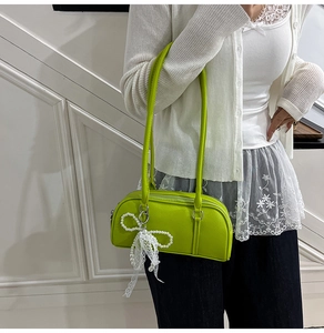 Detail of bright green pebble leather Boston bag featuring pearl bow and lace ribbon