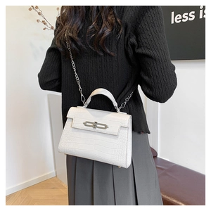 Detail of white crocodile pattern handbag with silver clasp and metal chain strap