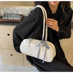 Detailed view of white ballet-style shoulder bag with blue checkered bow on leather strap