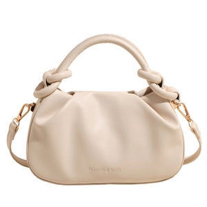 Detail of cream pleated bucket bag showing the soft texture and gold metal buckle