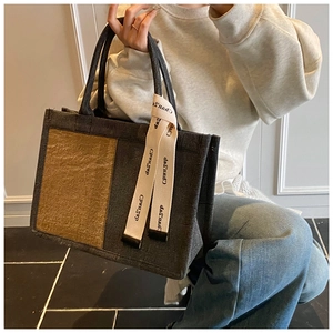 Detail of minimalist two-tone felt tote bag with decorative lettered ribbon and sturdy handles
