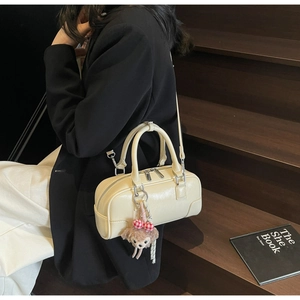 Detail of off-white mini Boston bag featuring a plush charm on a luxury leather handle