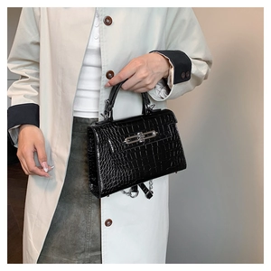 Detailed view of black crocodile pattern leather handbag with silver metallic buckle