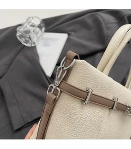 Détail du sac à main en cuir beige à motif litchi avec bordure brune et accents argentés