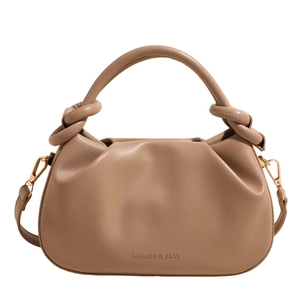 Detail of light brown pleated cloud bucket bag with knotted handle and brand lettering