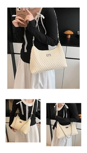Detail of a creamy beige pleated shoulder bag with metal buckle and chain strap