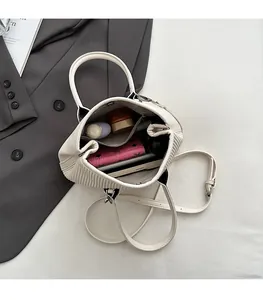 Spacious interior of a pleated off-white bucket bag showing personal items and zip pocket