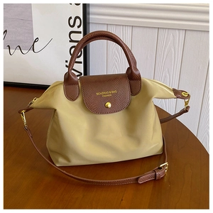 Detail of khaki oxford nylon tote bag featuring brown leather handles and gold zipper