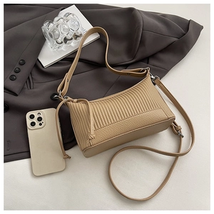 Detail of khaki pleated faux leather shoulder bag with drawstring accents on gray blazer