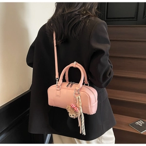 Close-up of pink leather Boston bag with textured finish and cute bear charm pendant