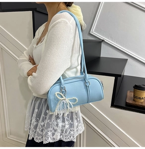 Detail of light blue lychee pattern leather Boston bag with pearl lace bow charm