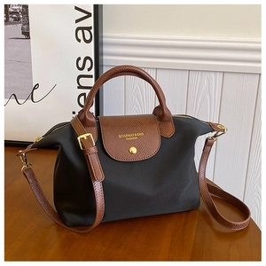 Close-up of black nylon tote bag with brown textured leather flap and golden hardware