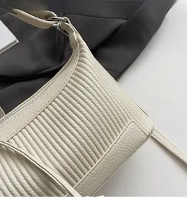Détail du sac à bandoulière crème en cuir avec matelassage plissé vertical et zip argenté
