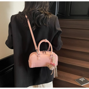 Detail of pink leather Boston bag featuring a cute character charm and a plaid bow