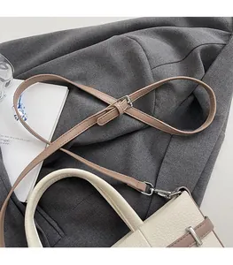 Détail d'un sac seau en cuir grainé avec boucle argentée et bandoulière marron