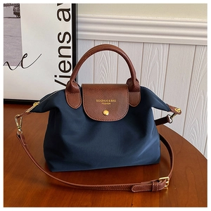 Detail of dark blue nylon tote bag with brown lychee leather handles and gold hardware