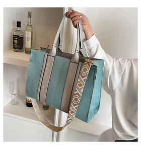 Détail d'un cabas en denim bleu clair avec bandoulière ethnique sur étagère