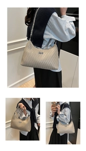 Detail of champagne pleated shoulder bag with silver chain strap and metal logo plaque