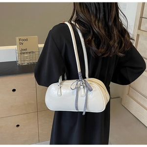 Detailed side view of white bow-accented cylinder bag featuring blue checkered ribbon
