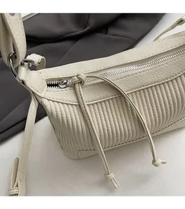 Détail du sac en cuir crème avec des plis verticaux et une fermeture éclair argentée