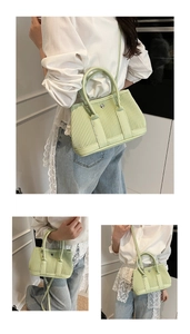 Close-up of light green pleated bucket bag showing metal magnetic buckle and texture