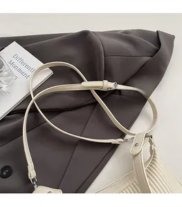 Détail de la bandoulière réglable et boucle en métal sur le sac plissé blanc cassé