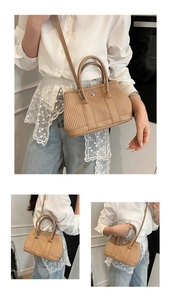 Detail of pleated khaki bucket bag with textured vertical folds and sleek metal ring closure