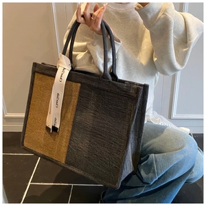 Close-up of color-block canvas tote bag with contrast stitching and decorative printed ribbon