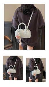 Detail of light blue pillow bag with plush bear charm and adjustable crossbody strap