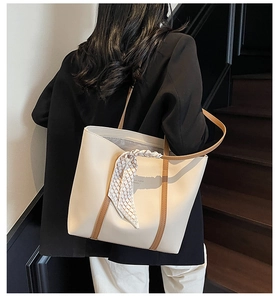 Detail of cream tote bag with brown edge piping and decorative checkered silk scarf on strap