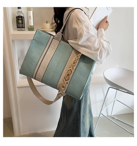 Détail du sac cabas en denim bleu avec bandoulière tissée et poignées beige
