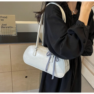 Detail showing white leather cylinder bag with blue plaid bow ribbon on black dress