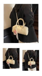 Detail of off-white Boston bag with lychee texture and bear charm on wooden stairs