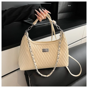 Detail view of beige pleated leather bag with silver metal twist lock and chain strap