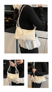 Detail of cream-white pleated underarm bag showing contrast textures and drawstring nodes