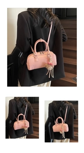 Detail of pink leather boston bag with cylindrical handles and a cute plush bear charm