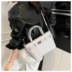 Détail du sac à main en cuir grainé gris avec fermoir rotatif porté par un mannequin