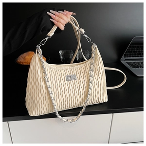Close-up of cream pleated shoulder bag with silver chain strap and twist lock detail