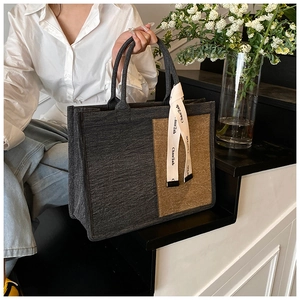 Detail of felt tote bag featuring color-block design and chic ribbon handle ornament