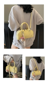 Detail view of bright yellow Boston leather bag with dual handles and metal zipper hardware