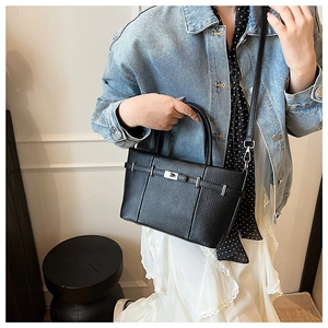 Détail du sac à main en cuir noir grainé avec fermoir argenté et bandoulière amovible