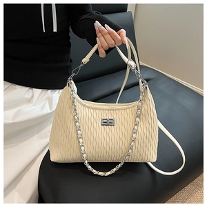 Detailed view of cream-colored pleated handbag with silver chain and metal clasp