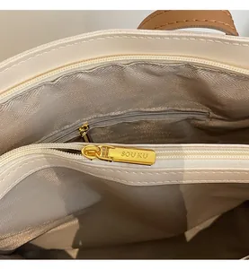 Detail view of large tote bag interior with herringbone lining and gold zipper pocket