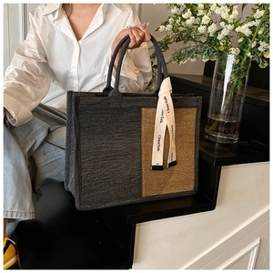 Detail of grey felt tote bag with contrast tan side panels and stylish lettered ribbon