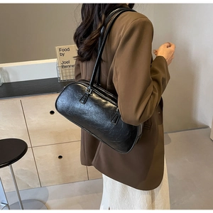 Detailed view of a black crinkled patent leather shoulder bag with slim straps