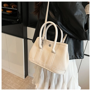 Close-up of a creamy white pleated bucket bag with silver metal buckle detail