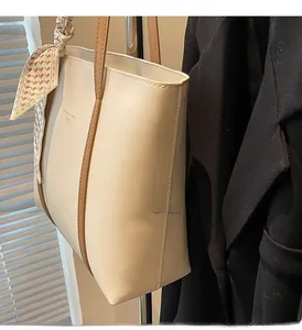 Detail of cream tote bag with contrast piping and yellow patterned decorative scarf